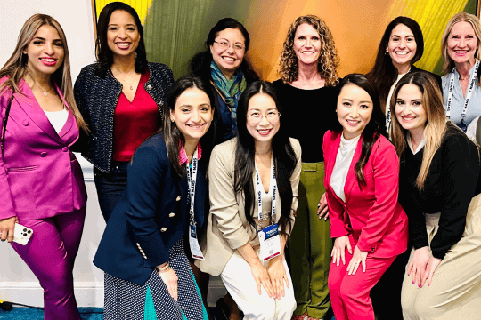 Group of diverse women in professional attire posing with NANS lanyards and badges.